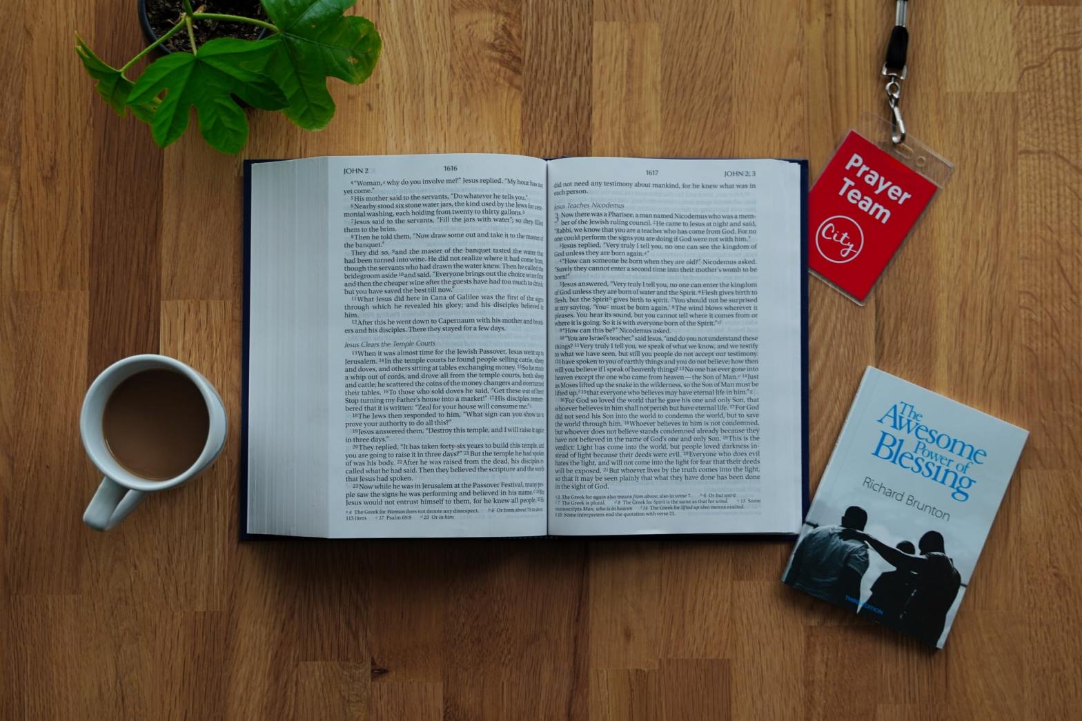 An open book with a tag, coffee, plant, and pocket book on the side.