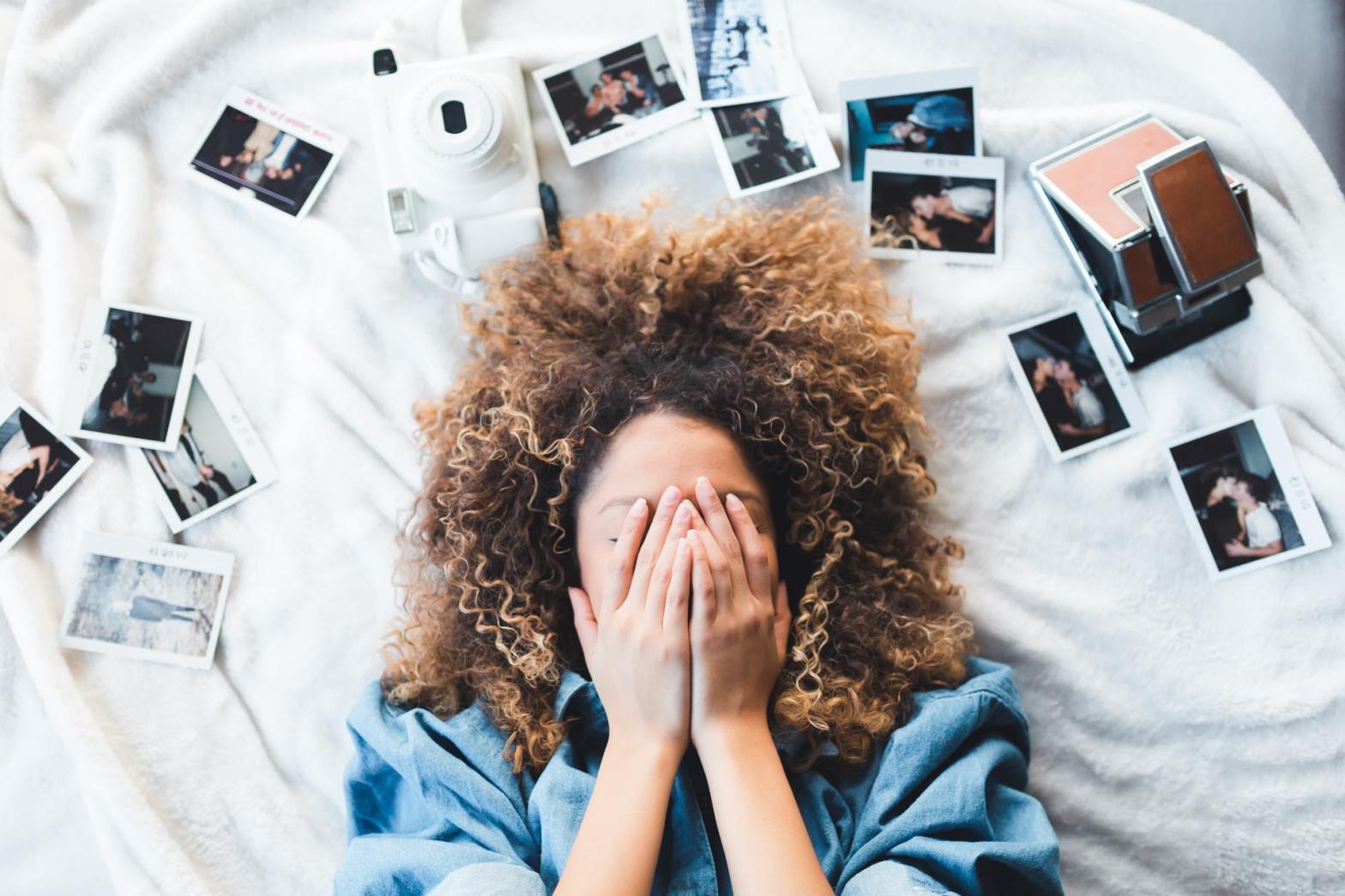 A woman covering her face while surrounded by photographs